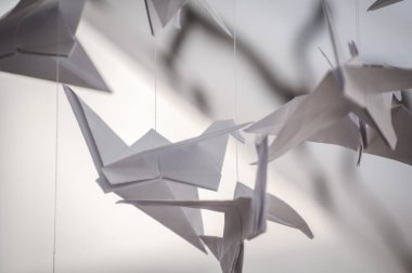 Japanese folded Origami cranes hanging on with strings. Hundreds handmade paper birds isolated with copy space. 1000 thousand crane tsuru sculpture topic. Symbol of peace, faith, health, wishes, hope