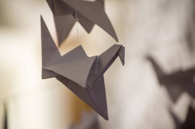 Japanese folded Origami cranes hanging on with strings. Hundreds handmade paper birds isolated with copy space. 1000 thousand crane tsuru sculpture topic. Symbol of peace, faith, health, wishes, hope