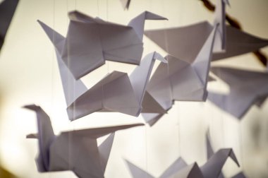 Japanese folded Origami cranes hanging on with strings. Hundreds handmade paper birds isolated with copy space. 1000 thousand crane tsuru sculpture topic. Symbol of peace, faith, health, wishes, hope