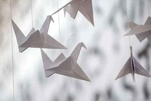 Japanese folded Origami cranes hanging on with strings. Hundreds handmade paper birds isolated with copy space. 1000 thousand crane tsuru sculpture topic. Symbol of peace, faith, health, wishes, hope