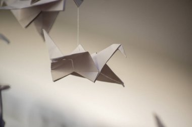 Japanese folded Origami cranes hanging on with strings. Hundreds handmade paper birds isolated with copy space. 1000 thousand crane tsuru sculpture topic. Symbol of peace, faith, health, wishes, hope