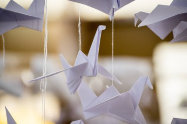 Japanese folded Origami cranes hanging on with strings. Hundreds handmade paper birds isolated with copy space. 1000 thousand crane tsuru sculpture topic. Symbol of peace, faith, health, wishes, hope