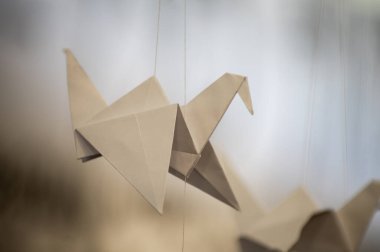 Japanese folded Origami cranes hanging on with strings. Hundreds handmade paper birds isolated with copy space. 1000 thousand crane tsuru sculpture topic. Symbol of peace, faith, health, wishes, hope