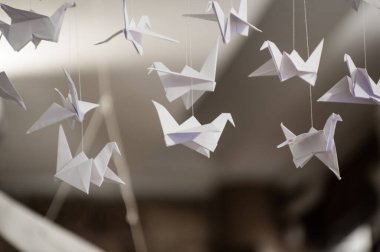 Japanese folded Origami cranes hanging on with strings. Hundreds handmade paper birds isolated with copy space. 1000 thousand crane tsuru sculpture topic. Symbol of peace, faith, health, wishes, hope