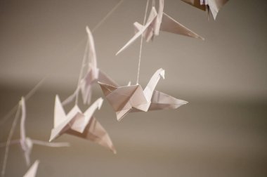 Japanese folded Origami cranes hanging on with strings. Hundreds handmade paper birds isolated with copy space. 1000 thousand crane tsuru sculpture topic. Symbol of peace, faith, health, wishes, hope