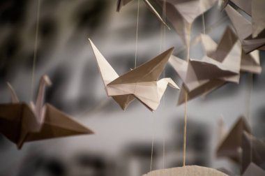 Japanese folded Origami cranes hanging on with strings. Hundreds handmade paper birds isolated with copy space. 1000 thousand crane tsuru sculpture topic. Symbol of peace, faith, health, wishes, hope