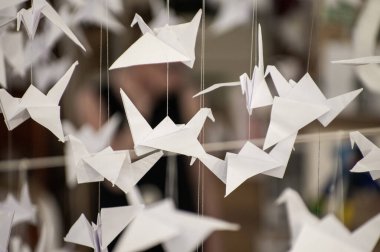 Japanese folded Origami cranes hanging on with strings. Hundreds handmade paper birds isolated with copy space. 1000 thousand crane tsuru sculpture topic. Symbol of peace, faith, health, wishes, hope