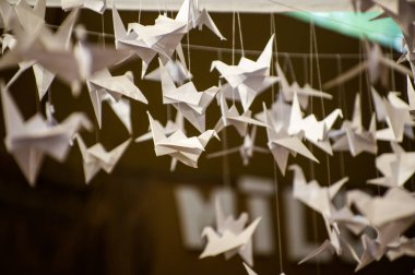 Japanese folded Origami cranes hanging on with strings. Hundreds handmade paper birds isolated with copy space. 1000 thousand crane tsuru sculpture topic. Symbol of peace, faith, health, wishes, hope