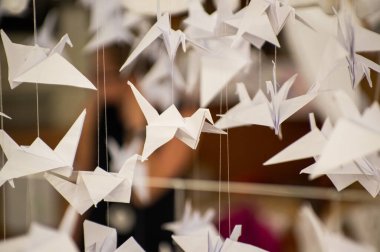 Japanese folded Origami cranes hanging on with strings. Hundreds handmade paper birds isolated with copy space. 1000 thousand crane tsuru sculpture topic. Symbol of peace, faith, health, wishes, hope
