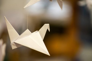 Japanese folded Origami cranes hanging on with strings. Hundreds handmade paper birds isolated with copy space. 1000 thousand crane tsuru sculpture topic. Symbol of peace, faith, health, wishes, hope