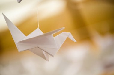 Japanese folded Origami cranes hanging on with strings. Hundreds handmade paper birds isolated with copy space. 1000 thousand crane tsuru sculpture topic. Symbol of peace, faith, health, wishes, hope