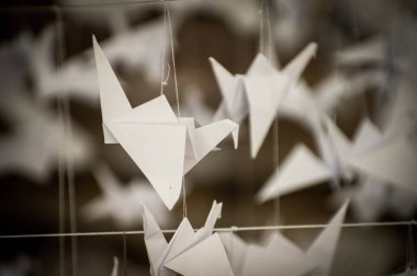 Japanese folded Origami cranes hanging on with strings. Hundreds handmade paper birds isolated with copy space. 1000 thousand crane tsuru sculpture topic. Symbol of peace, faith, health, wishes, hope