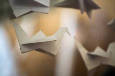 Japanese folded Origami cranes hanging on with strings. Hundreds handmade paper birds isolated with copy space. 1000 thousand crane tsuru sculpture topic. Symbol of peace, faith, health, wishes, hope