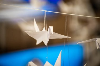 Japanese folded Origami cranes hanging on with strings. Hundreds handmade paper birds isolated with copy space. 1000 thousand crane tsuru sculpture topic. Symbol of peace, faith, health, wishes, hope