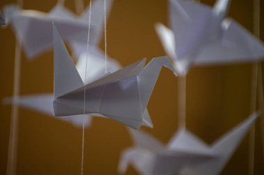 Japanese folded Origami cranes hanging on with strings. Hundreds handmade paper birds isolated with copy space. 1000 thousand crane tsuru sculpture topic. Symbol of peace, faith, health, wishes, hope