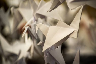 Japanese folded Origami cranes hanging on with strings. Hundreds handmade paper birds isolated with copy space. 1000 thousand crane tsuru sculpture topic. Symbol of peace, faith, health, wishes, hope