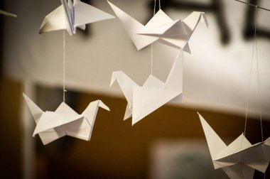 Japanese folded Origami cranes hanging on with strings. Hundreds handmade paper birds isolated with copy space. 1000 thousand crane tsuru sculpture topic. Symbol of peace, faith, health, wishes, hope