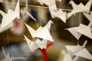 Japanese folded Origami cranes hanging on with strings. Hundreds handmade paper birds isolated with copy space. 1000 thousand crane tsuru sculpture topic. Symbol of peace, faith, health, wishes, hope