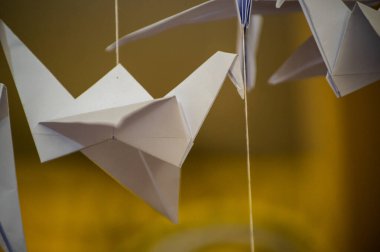 Japanese folded Origami cranes hanging on with strings. Hundreds handmade paper birds isolated with copy space. 1000 thousand crane tsuru sculpture topic. Symbol of peace, faith, health, wishes, hope