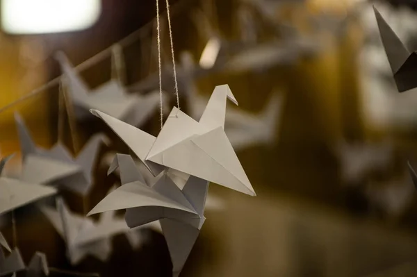 Japanese folded Origami cranes hanging on with strings. Hundreds handmade paper birds isolated with copy space. 1000 thousand crane tsuru sculpture topic. Symbol of peace, faith, health, wishes, hope