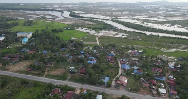 アジアの村を通る田舎道の空中軌道撮影 背景の川と氾濫原 — ストック動画