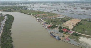 Aerial drone shot over the Praek Tuek Chhu River from the Gulf of Thailand.  Salt fields as backdrop