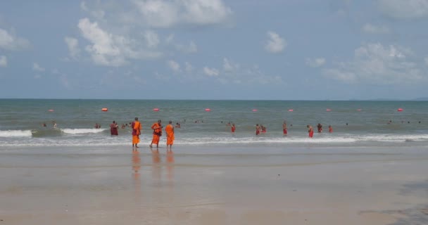 カンボジアのシアヌークビル 2023年 他の人が背景に泳いでいる間 ビーチに立っている若い僧侶のバックビュー — ストック動画