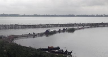 Gece boyunca bambu köprüsünden geçen yerel halk ve araçların nehir kenarını görüntüleyin 