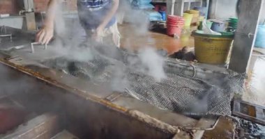 Sihanoukville, Kamboçya - 04.29.2023: İşçi, kaynayan karideslerin kapaklarını tanklara yerleştiriyor