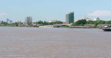 Mekong Nehri 'nde yerel halkı taşıyan feribot. Arkaplan olarak Phnom Penh 