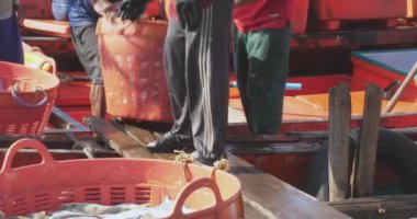 Sihanoukville, Kamboçya - 06.09.2023; İki balıkçı tekneden limana kadar tahta bir tahtanın üzerinde yürürken balık dolu ağır bir sepet taşıyor.