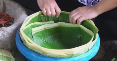 Bir kadının yanına muz yapraklarıyla plastik bir sepet sar. Bu sepet pirinç eriştesi koymak için kullanılacak..