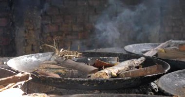 Soya sütü kaynatmak için kullanılacak odun parçalarını içeren paslı bir tavaya yakın durun. 