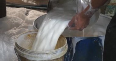 Bir kovadan diğerine soya sütü döken bir işçiye yaklaş.