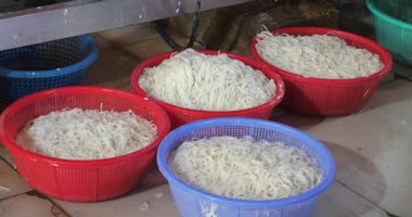 Bu yakın plan fabrika zemininde içi taze pirinç eriştesi dolu plastik sepetleri gösteriyor..