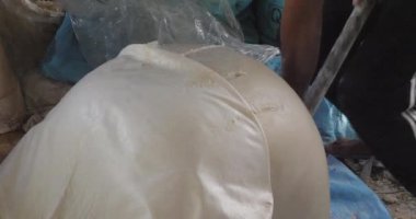 Pirinç hamurunu yoğurma makinesine koymadan önce kesen bir adamın yakın çekimi..
