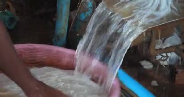 Yakın planda, bir işçi içi taze kesilmiş pirinç eriştesiyle dolu plastik bir sepeti boş bir sepetle değiştirir.