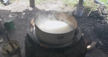 Geleneksel şeker avuçlayıcıları. Yüksek bir açıdan ve yakın planda yanan odun ateşinde pişen bir tavadan. İçinde palmiye şekeri pişiyor.