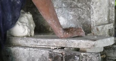 Yakın çekim, yoğurma makinesinde pirinç hamuru üzerinde çalışan bir adamı gösteriyor.