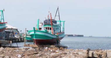 Kamera, ahşap bir balıkçı teknesinin denize geri kaydığı anı yakalıyor. Suyun kıyısındaki hareketli kayıkhanede yenilenmiş.