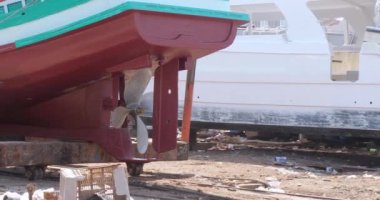  Ahşap bir balıkçı teknesinin arka görüntüsü yenilenmiş bir şekilde kayıkhaneye süzülerek su kenarına doğru gidiyor.