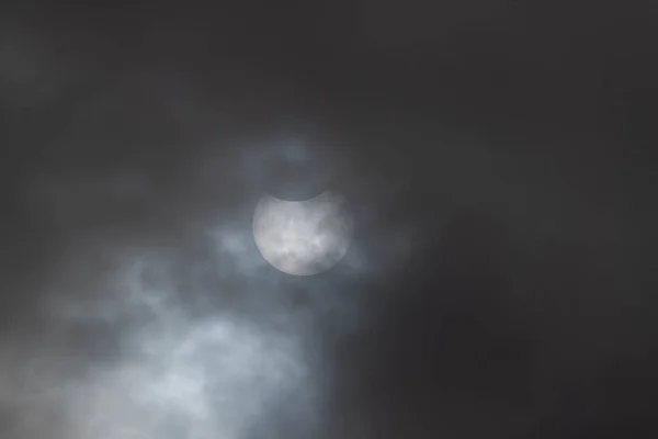 曇りの日に日食 曇った空は 部分日食の間 雲の薄い層の後ろから見ることができます 太陽の上部は月によって隠されている 太陽の下にスポットがあります — ストック写真
