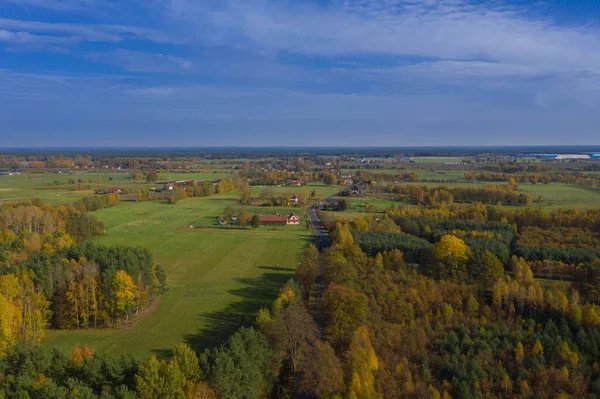 A vast plain covered with forests, in the distance you can see fields and meadows among which you can see the buildings of a nearby village. Photo from the drone. This is the Marches.