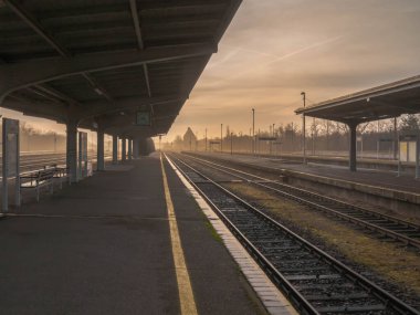 Polonya 'nın Zagan kentindeki tren istasyonunda bir platform. Platform metal direklerle desteklenen bir sığınakla korunuyor. İki tarafta da tren rayları var..