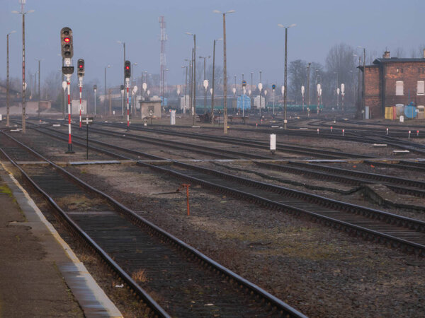 Railway station in the city of Zagan in Poland. Numerous railway tracks leading to and leaving the station, forming turnouts. You can see railway switches and traffic lights,