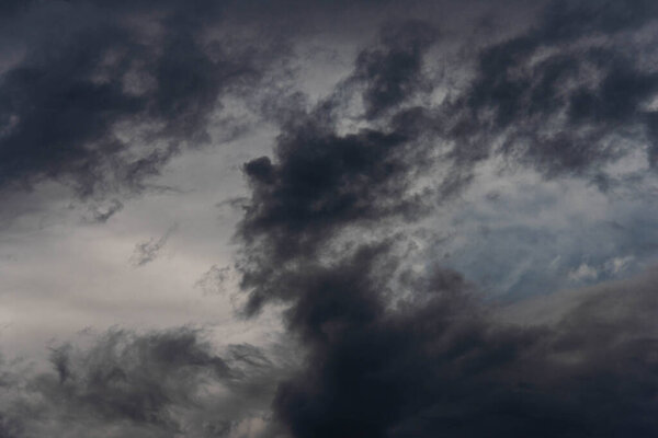 The sky is covered with a thin layer of dark gray clouds. Sunlight is visible through the clouds.