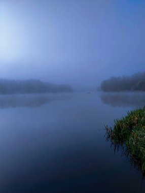 Gölde bahar sabahı. Suyun yüzeyinde güneş ışığının içinden geçtiği kalın bir bulut yüzer..