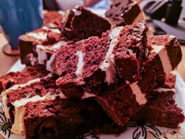 Beyaz kremayla kaplı çikolatalı pasta, porselen bir tabakta yatıyor..