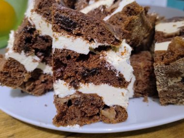 Beyaz kremayla kaplı çikolatalı pasta, porselen bir tabakta yatıyor..