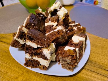 Beyaz kremayla kaplı çikolatalı pasta, porselen bir tabakta yatıyor..